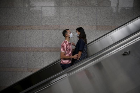 A couple wearing masks to prevent contracting Middle East Respiratory Syndrome (MERS) looks at each other as they ride on an escalator in Seoul, South Korea, June 11, 2015.