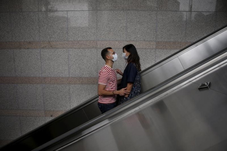 A couple wears masks as they ride on an escalator. 