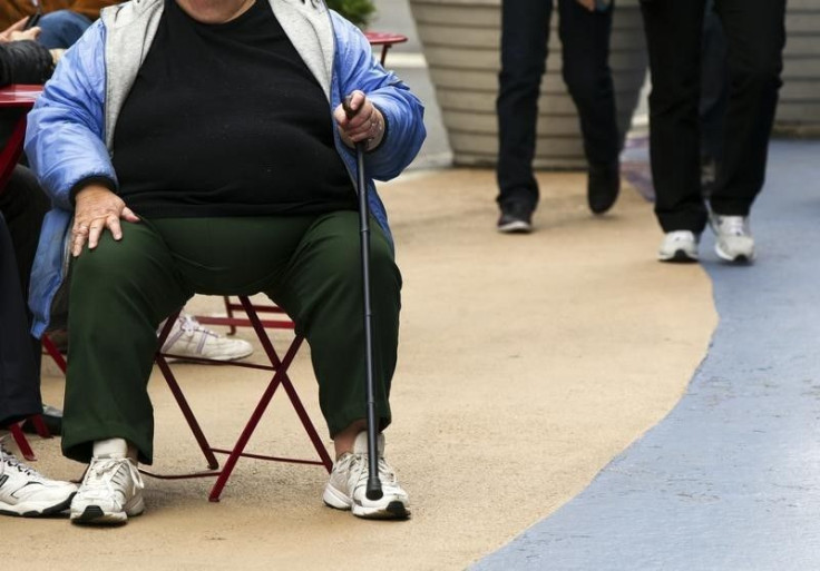 An obese woman sits on a chair. 