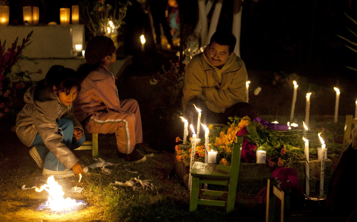 Family visit grave with flowers and candles on the Day of the Dead