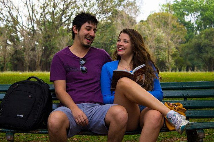 Guy and woman laughing on bench