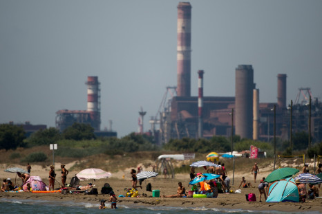 People swim next to an industrial area in Fos-sur Mer, southern France while ozone pollution levels peaked in the area in 2015.