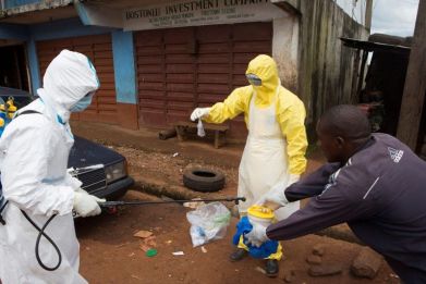 Health workers in protective equipment handle a sample taken from the body of someone who is suspected to have died from Ebola virus, near Rokupa Hospital, Freetown.