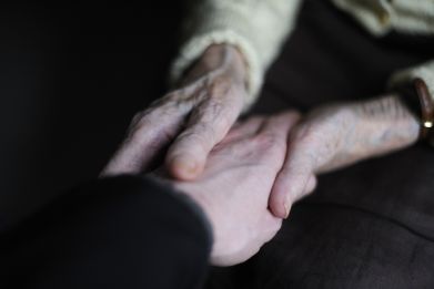 A woman, suffering from Alzheimer's desease, holds the hand of a relative in a retirement house in Angervilliers, eastern France, March 18, 2011.