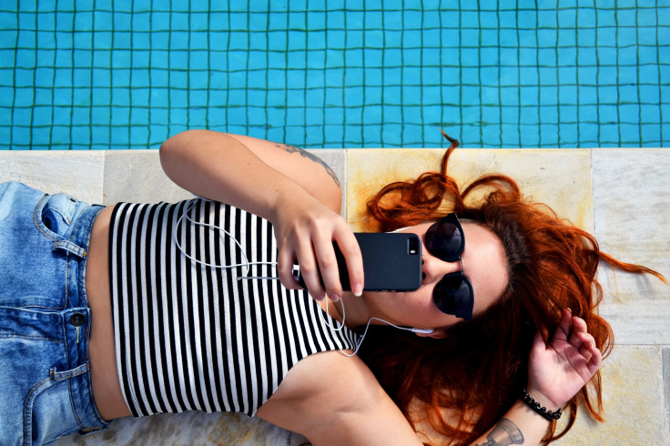 Woman on phone lying next to pool