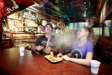 Two Canadians smoke marijuana with a bong at the New Amsterdam Cafe in Vancouver, British Columbia. New research shows cannabis use can boost one's motivation to exercise.