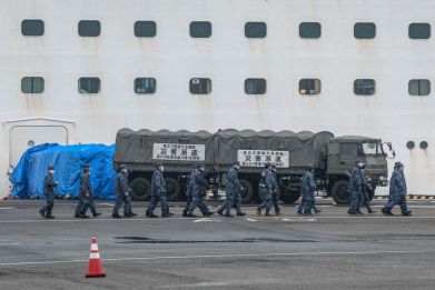 YOKOHAMA, JAPAN - FEBRUARY 16: Japan Self-Defense Force personnel walk past the Diamond Princess cruise ship as it remains in quarantine at Daikoku Pier on February 16, 2020 in Yokohama, Japan. The United States has become the first country to offer to repatriate citizens on the Diamond Princess cruise ship while it remains quarantined in Yokohama Port as at least 285 passengers and crew onboard have tested positive for the COVID-19 virus. Including cases onboard the ship, 338 people in Japan have now been diagnosed with COVID-19 making it the worst affected country outside of China.