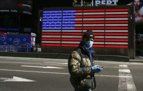 A man wears a face mask as he check his phone in Times Square on March 22, 2020 in New York City. - Coronavirus deaths soared across the United States and Europe on despite heightened restrictions as hospitals scrambled to find ventilators.