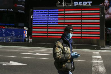A man wears a face mask as he check his phone in Times Square on March 22, 2020 in New York City. - Coronavirus deaths soared across the United States and Europe on despite heightened restrictions as hospitals scrambled to find ventilators.