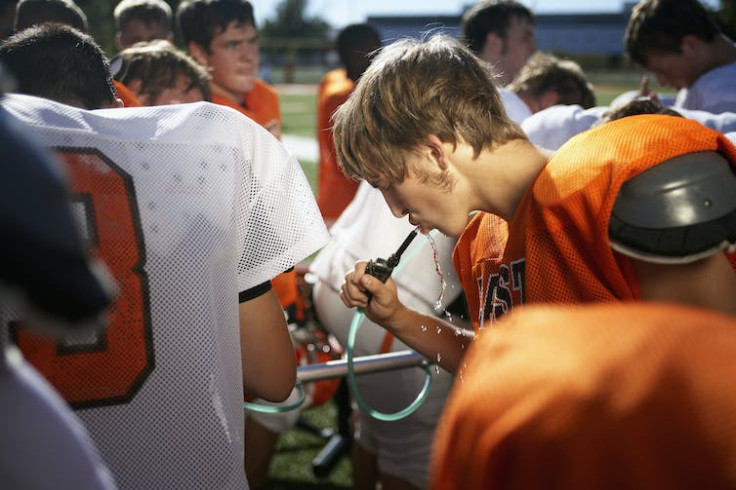 A young football player drinking water.