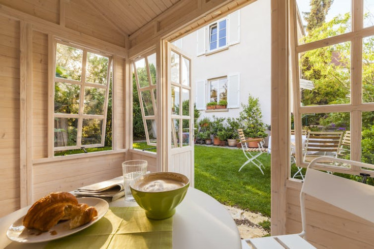 A table with a cooked meal on it inside of a room with doors and windows open.